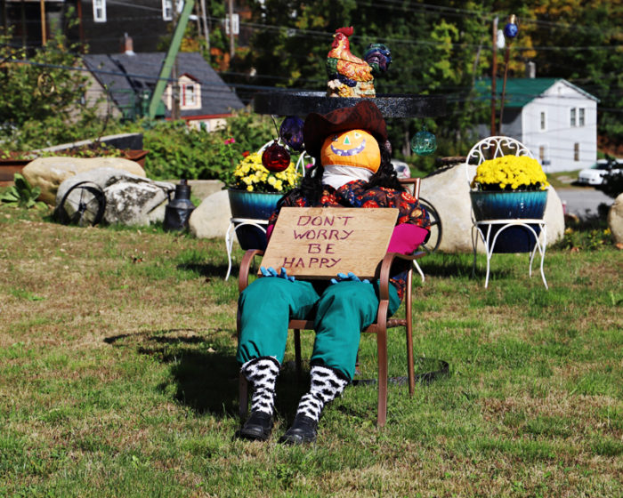 Scarecrow with a pumpkin head sitting in a lawn chair in Bristol, NH Central Square